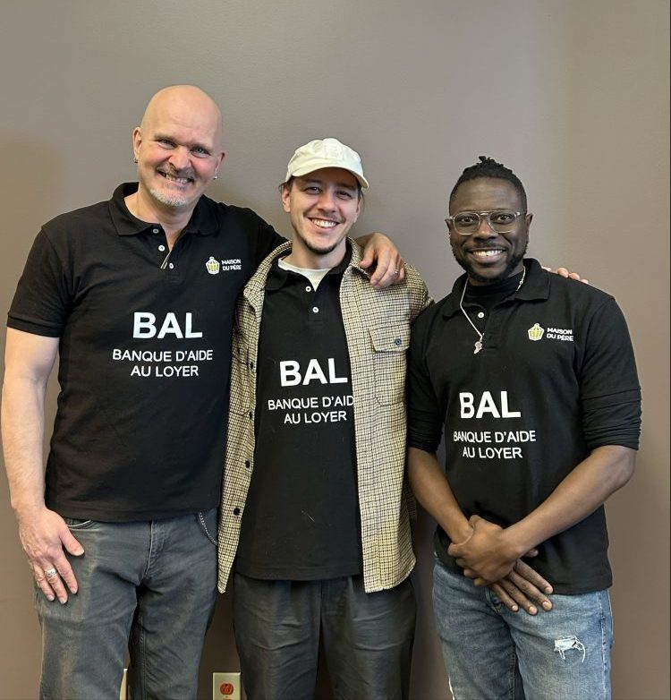 Trois hommes souriants portant des chandails noirs avec l'inscription BAL Banque d'aide au loyer.